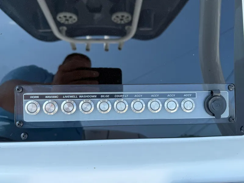 Slide: The Image of Control panel of a 2018 Tidewater 232 LXF boat with labeled buttons and 12V outlet. - 12