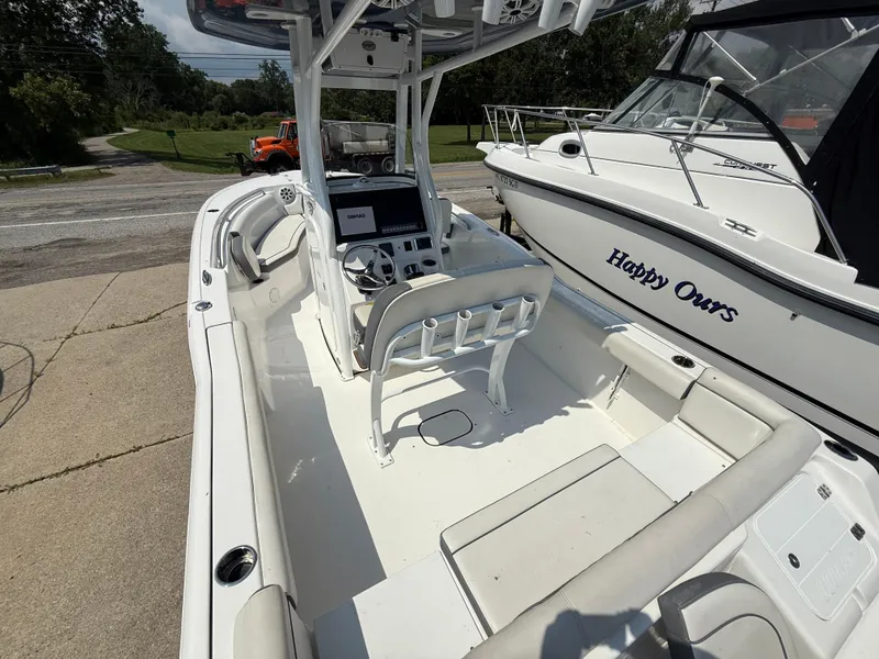 Slide: The Image of 2018 Tidewater 232 LXF boat interior with console and seating, docked beside another boat. - 9