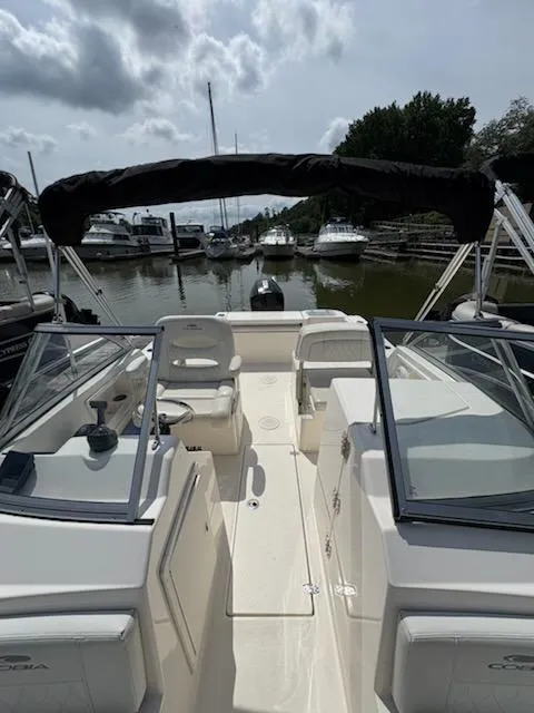 Slide: The Image of 2023 Cobia 220 Dual Console boat docked in a marina under cloudy skies. - 10