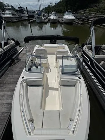 Slide: The Image of 2023 Cobia 220 Dual Console boat docked at marina, surrounded by other vessels. - 5