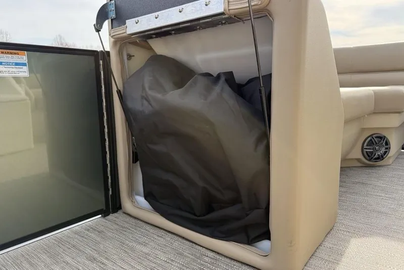 Slide: The Image of Storage compartment on 2025 Godfrey Xperience 2286 SBX boat, featuring beige interior and speaker. - 16