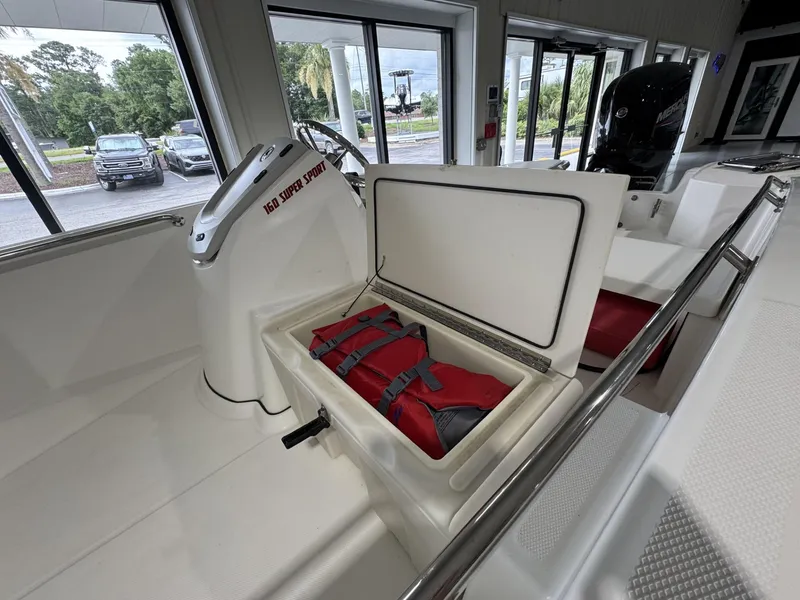 Slide: The Image of 2023 Boston Whaler 160 Super Sport boat interior with storage compartment and life jackets. - 12