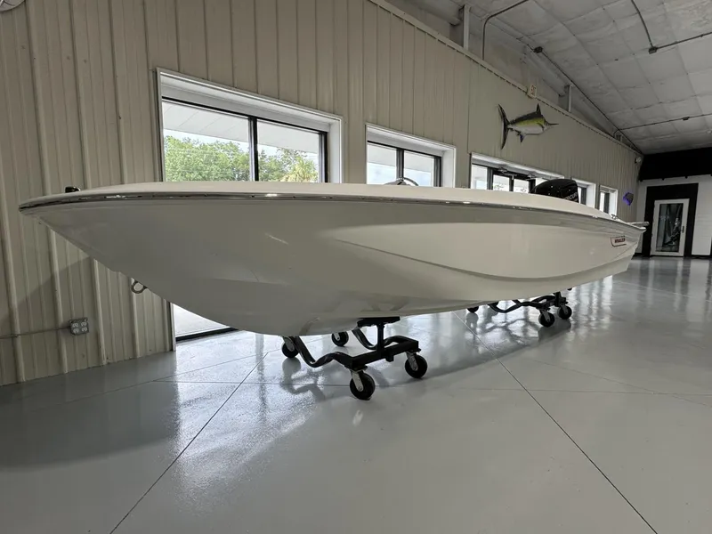 Slide: The Image of 2023 Boston Whaler 160 Super Sport boat displayed indoors on wheeled stands. - 2