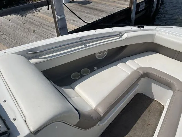 Slide: The Image of 2004 Cobalt 226 boat interior with white seating and cup holders near dock. - 17