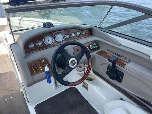 Slide: The Image of 2004 Cobalt 226 boat dashboard with steering wheel and control panel by the water. - 9
