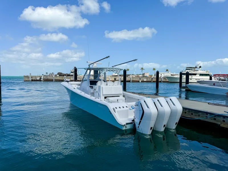 Slide: The Image of 2025 Front Runner 36 cc boat docked, featuring triple outboard engines, under a clear blue sky. - 2