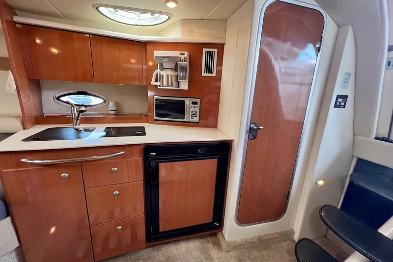 Slide: The Image of 2006 Maxum 3100 SE yacht interior kitchen with wood cabinets, sink, microwave, and fridge. - 16