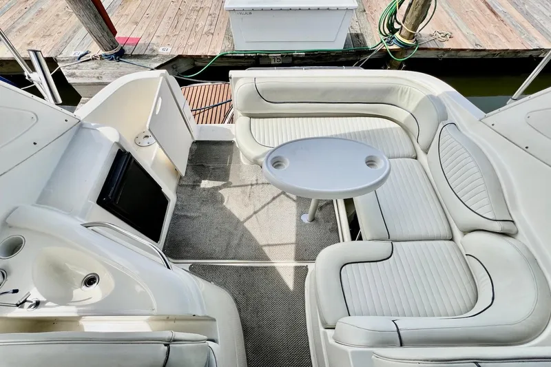Slide: The Image of 2006 Maxum 3100 SE boat interior with white seating and round table at dock. - 7