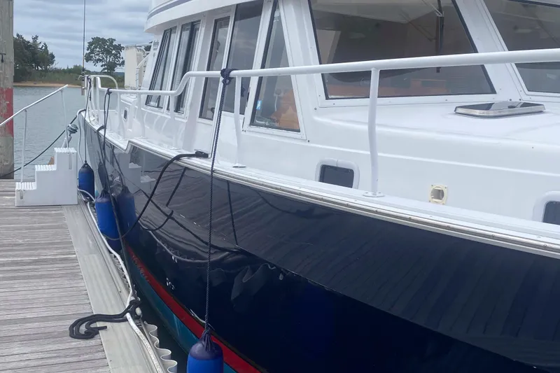 Slide: The Image of 1999 Mainship 430 Trawler docked, showcasing sleek design and blue hull. - 10