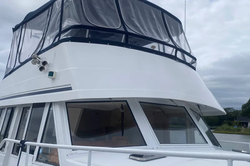 Slide: The Image of 1999 Mainship 430 Trawler with enclosed flybridge, docked on a cloudy day. - 11