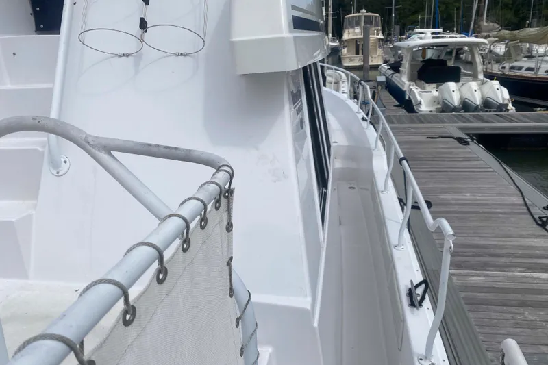 Slide: The Image of 1999 Mainship 430 Trawler docked at marina, side view with railing and walkway. - 18