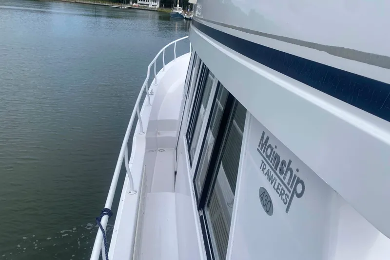 Slide: The Image of Side view of a 1999 Mainship 430 Trawler on calm water. - 19