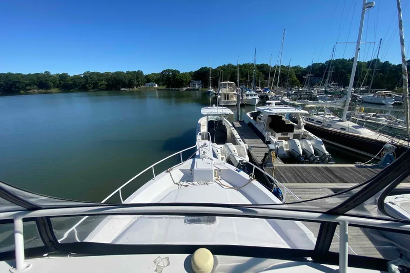 Slide: The Image of 1999 Mainship 430 Trawler docked at a serene marina with clear blue skies. - 2
