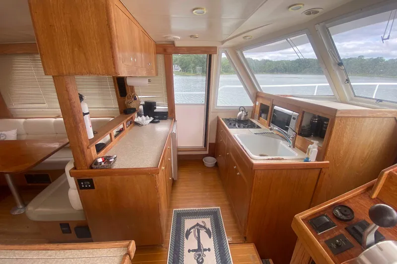 Slide: The Image of Interior of 1999 Mainship 430 Trawler with kitchen and dining area, featuring wood cabinetry. - 21