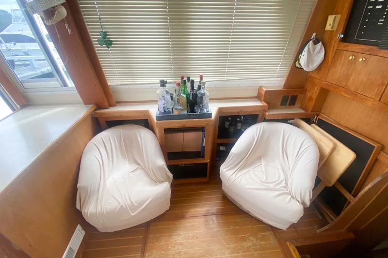 Slide: The Image of Interior of 1999 Mainship 430 Trawler with two white chairs and a small bar area. - 27