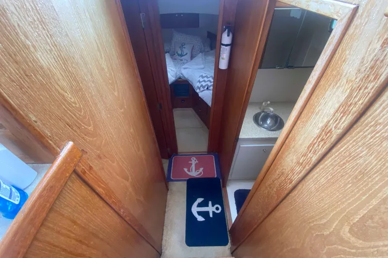 Slide: The Image of 1999 Mainship 430 Trawler interior with wooden paneling, nautical-themed rugs, and compact sink area. - 29
