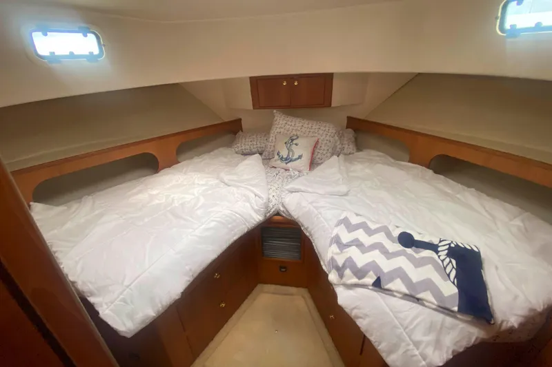 Slide: The Image of 1999 Mainship 430 Trawler cabin with twin beds, nautical decor, and wooden storage. - 31