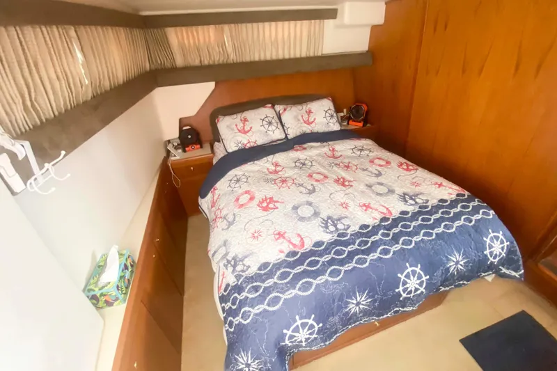 Slide: The Image of Cozy bedroom in 1999 Mainship 430 Trawler with nautical-themed bedding and wooden interior. - 36