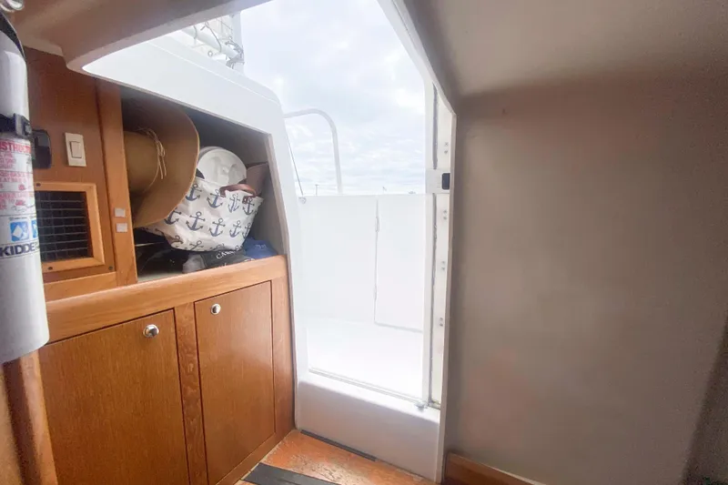 Slide: The Image of Interior view of 1999 Mainship 430 Trawler with wooden cabinets and open door to deck. - 40