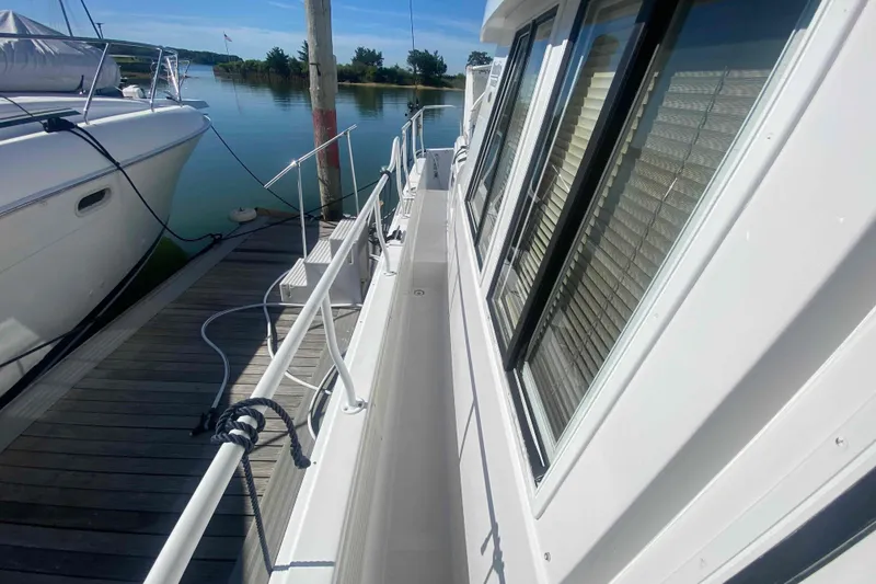 Slide: The Image of 1999 Mainship 430 Trawler docked, showcasing side deck and windows. - 5