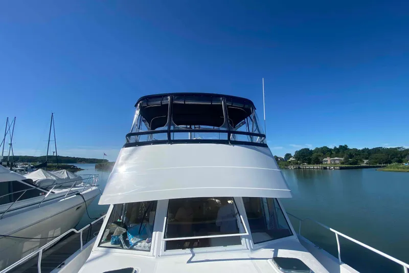Slide: The Image of 1999 Mainship 430 Trawler docked on a sunny day, surrounded by calm waters. - 7