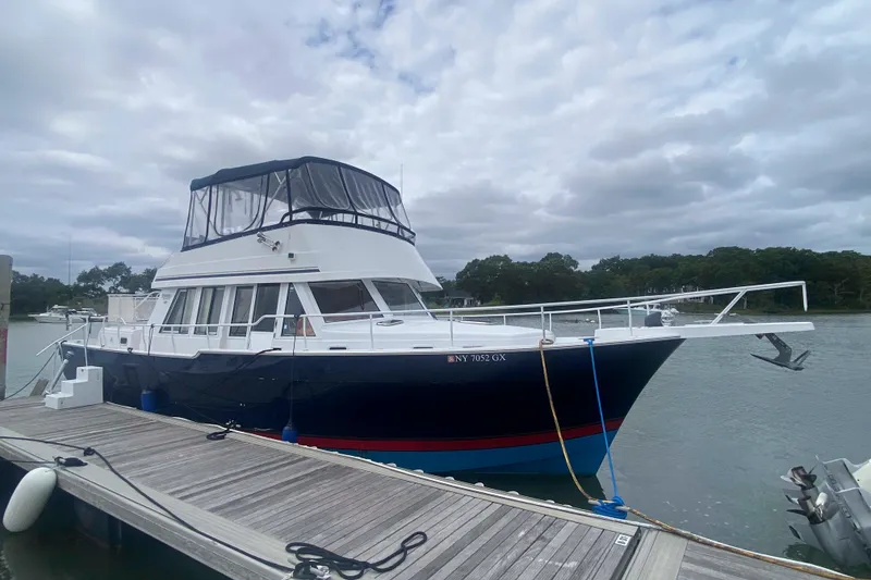 Slide: The Image of 1999 Mainship 430 Trawler docked, featuring a blue hull and enclosed flybridge. - 8
