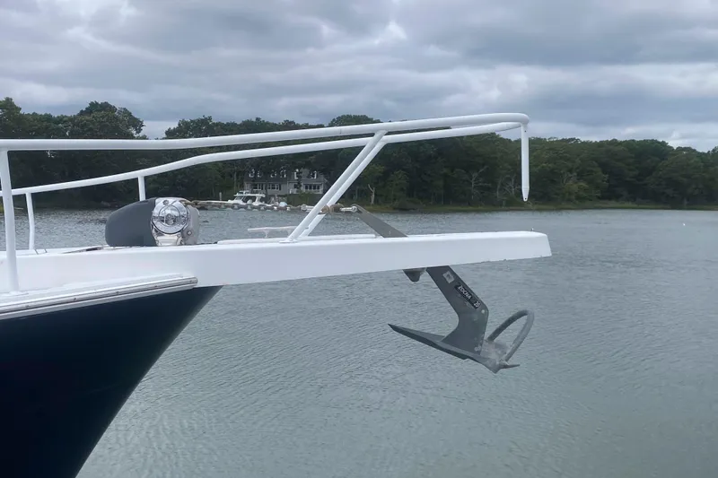 Slide: The Image of 1999 Mainship 430 Trawler with anchor, docked on a calm lake under cloudy skies. - 9