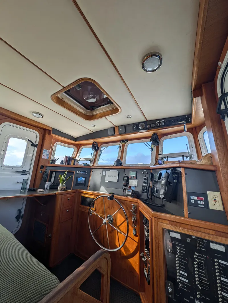 Slide: The Image of 2002 Nordhavn Trawler helm with navigation equipment, wooden interior, and panoramic windows. - 14