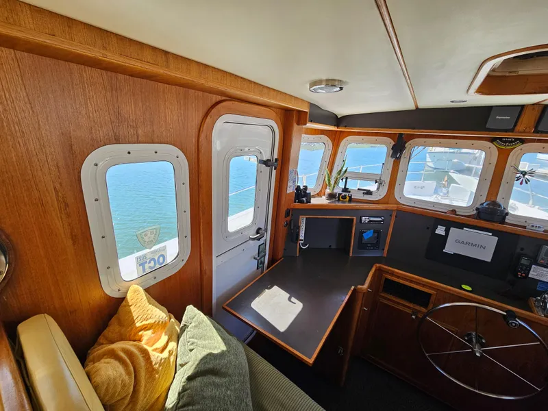 Slide: The Image of Interior of a 2002 Nordhavn Trawler with wooden paneling and navigation equipment. - 20