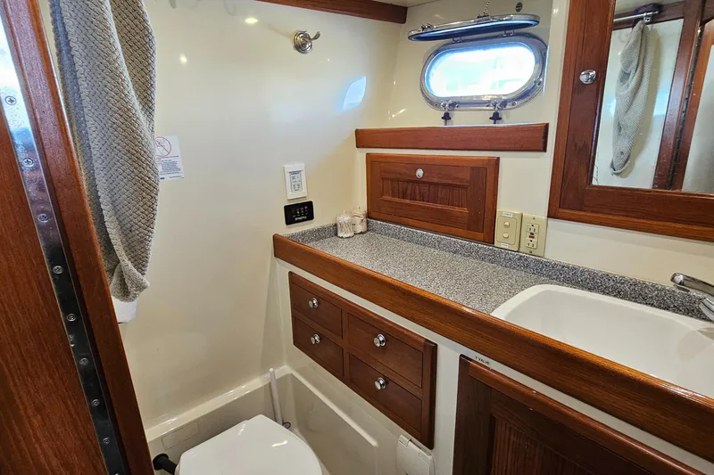 Slide: The Image of 2002 Nordhavn Trawler bathroom with wood accents, sink, and porthole window. - 33
