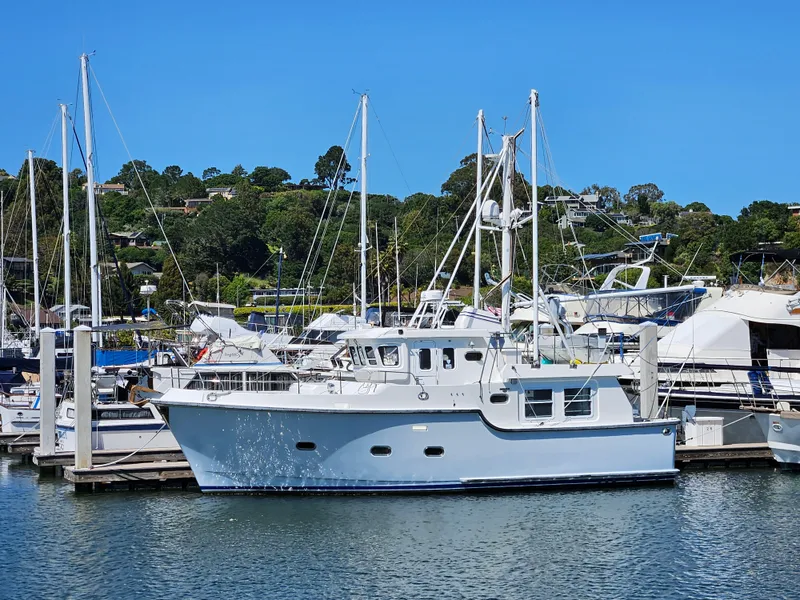 Slide: The Image of 2002 Nordhavn Trawler docked at marina, surrounded by sailboats and lush greenery. - 42