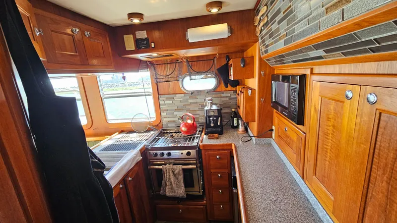 Slide: The Image of 2002 Nordhavn Trawler kitchen with wooden cabinets, stove, and modern appliances. - 9
