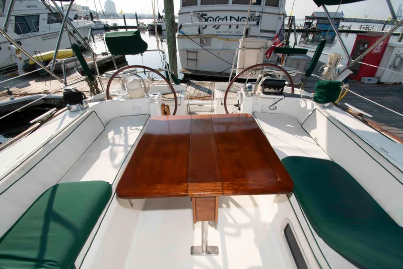 Slide: The Image of Cockpit of 2002 Beneteau 473 sailboat with wooden table and green cushions at dock. - 10