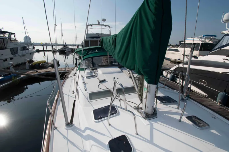 Slide: The Image of Beneteau 473 sailboat from 2002 docked at a marina, featuring green sail cover. - 14