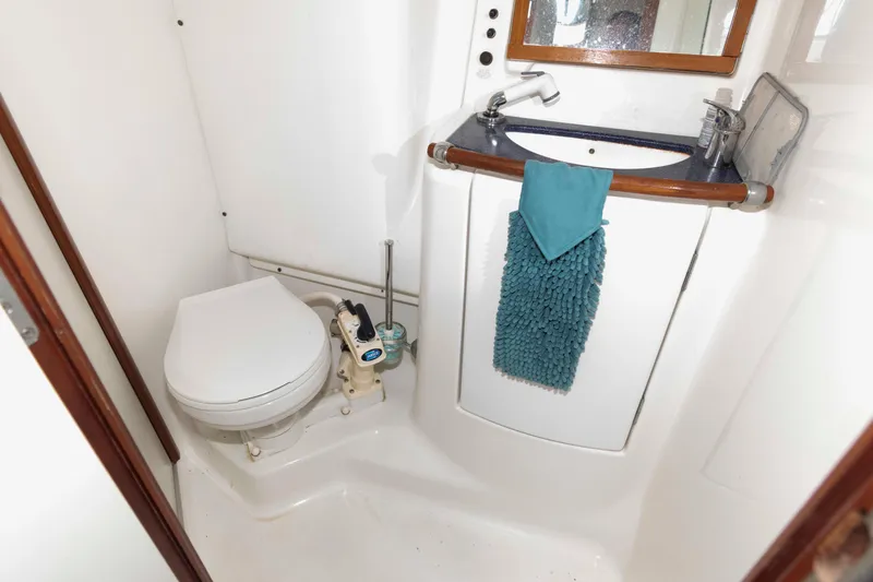 Slide: The Image of Beneteau 473 (2002) yacht bathroom with toilet, sink, and teal towel. - 27