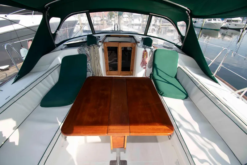 Slide: The Image of Cockpit of 2002 Beneteau 473 sailboat with wooden table and green cushions. - 9