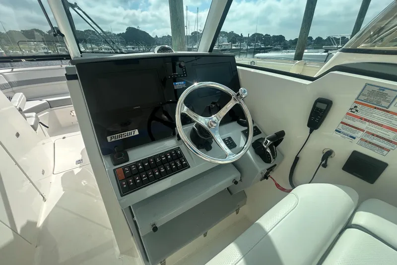 Slide: The Image of 2023 Pursuit DC326 boat helm with dual Garmin displays and modern controls. - 12