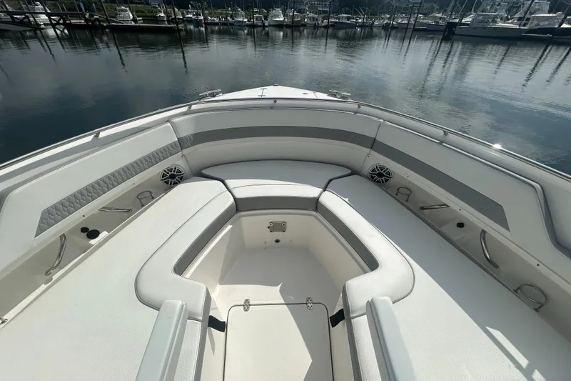 Slide: The Image of 2023 Pursuit DC326 boat interior with cushioned seating and harbor view. - 18