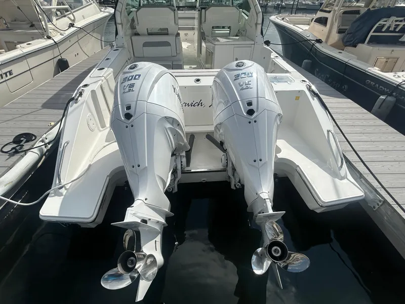 Slide: The Image of 2023 Pursuit DC326 boat docked, featuring dual outboard engines and spacious seating. - 2