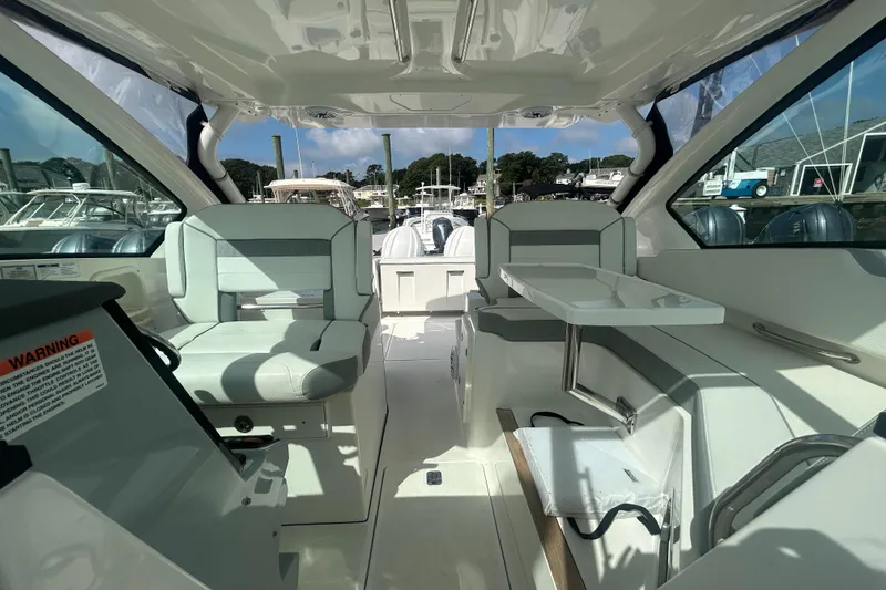 Slide: The Image of 2023 Pursuit DC326 boat interior with seating and table, docked at marina. - 20