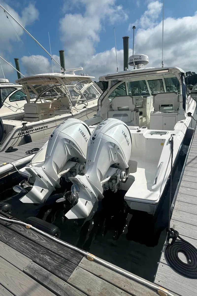 Slide: The Image of 2023 Pursuit DC326 boat docked with twin Yamaha outboard engines under a clear sky. - 4