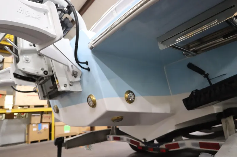 Slide: The Image of 2024 SeaCraft 23CC boat rear view, showcasing hull and motor details in a warehouse setting. - 11