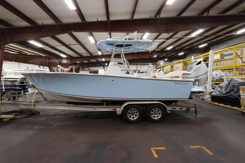 Slide: The Image of 2024 SeaCraft 23CC boat in warehouse, light blue hull, on trailer. - 2