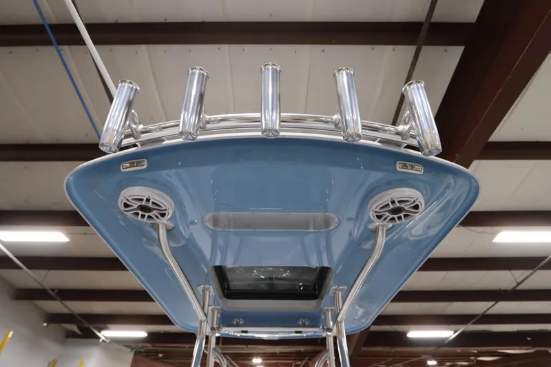 Slide: The Image of 2024 SeaCraft 23CC boat with rod holders and speakers, viewed from below in a warehouse. - 49