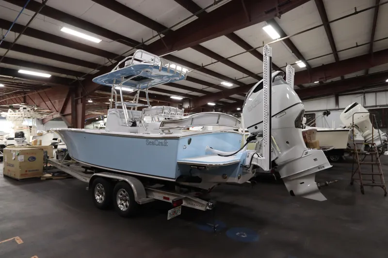 Slide: The Image of 2024 SeaCraft 23CC boat in a warehouse, featuring dual outboard motors. - 6