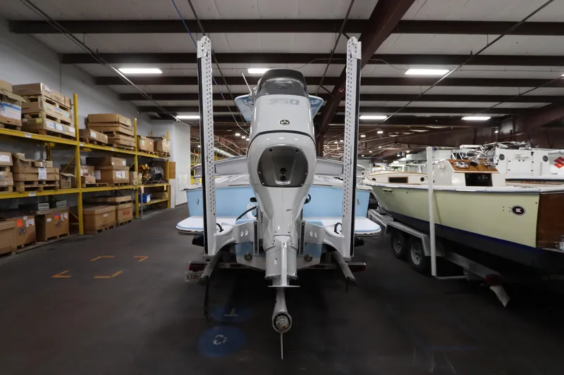 Slide: The Image of 2024 SeaCraft 23CC boat in warehouse, rear view with motor and storage shelves. - 7