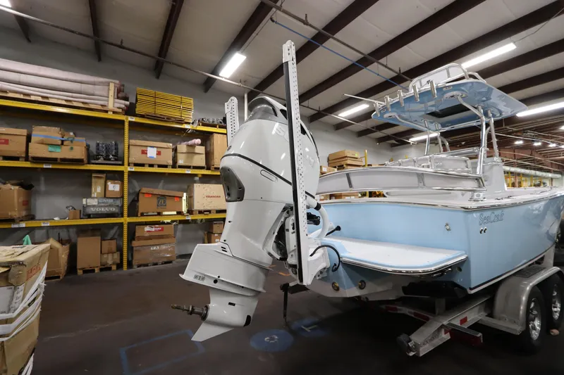 Slide: The Image of 2024 SeaCraft 23CC boat in warehouse, showcasing outboard motor and light blue hull. - 8