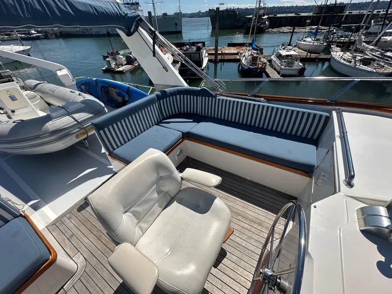 Slide: The Image of 1985 Ocean Alexander Pilothouse yacht deck with seating and steering wheel, docked at marina. - 20
