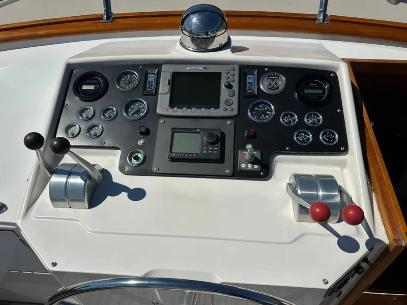 Slide: The Image of 1985 Ocean Alexander Pilothouse control panel with gauges, levers, and navigation equipment. - 24