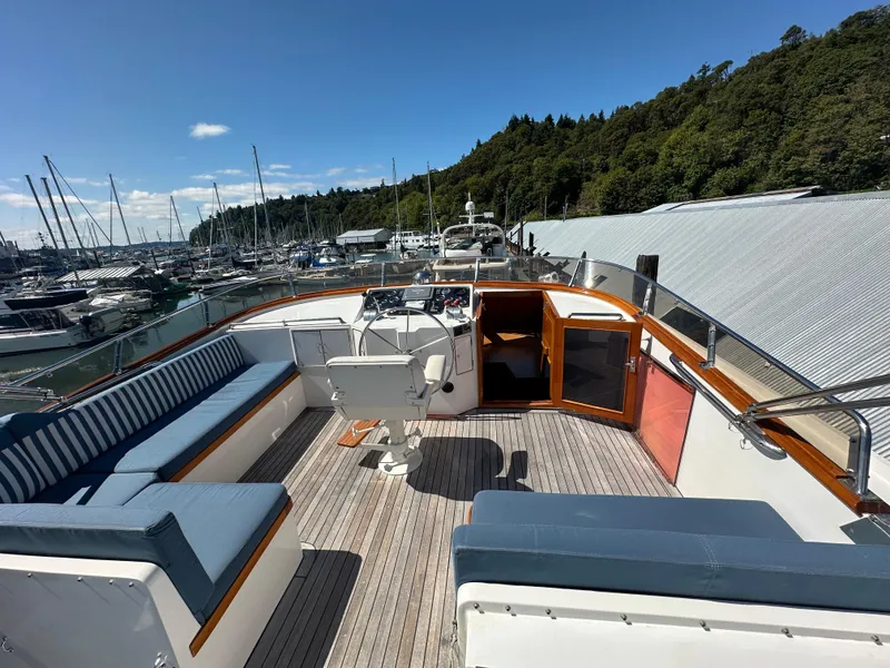 Slide: The Image of 1985 Ocean Alexander Pilothouse yacht deck with seating, helm, and marina view. - 26